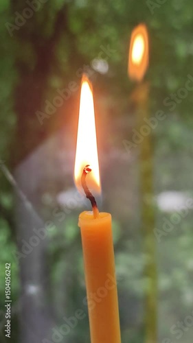 Single Candle Flame Glowing Warmly with Reflection in Rainy Window
