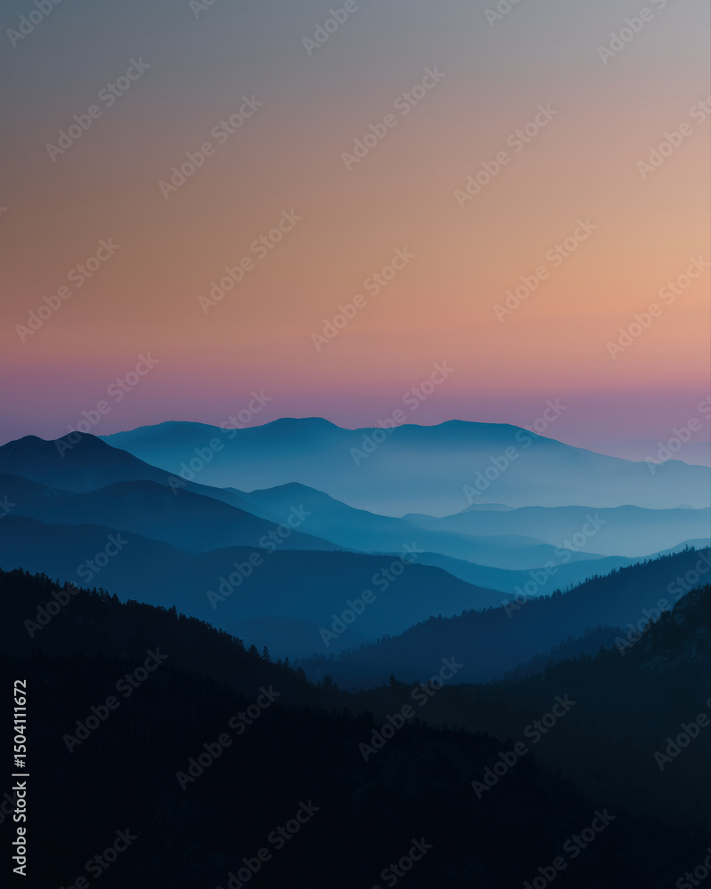 Obraz premium Misty mountain range at sunset with layered blue hills and soft gradient sky creating peaceful and serene atmosphere in nature