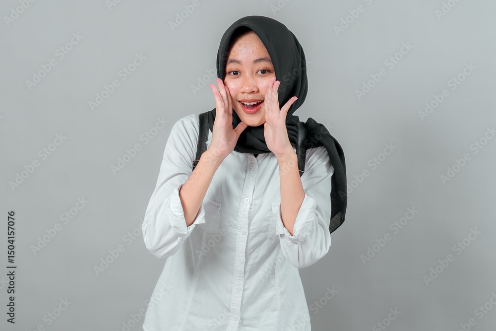 Happy Muslim teenage girl in a black hijab and white shirt smiling while shouting with both hands near her face, wearing a backpack, excited for the first day back to school. Happy Muslim teenage girl in a black hijab and white shirt smiling while shouting with both hands near her face, wearing a backpack, excited for the first day back to school.