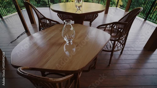 Wooden terrace with wicker chairs and tables overlooking lush green forest

