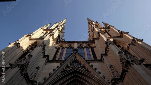 Gothic cathedral with twin spires and intricate detailing against clear blue sky


