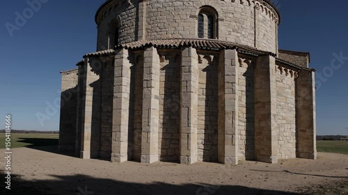 Romanesque stone church with rounded apse and thick vertical buttresses

