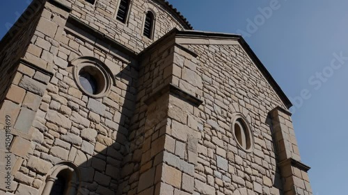 Romanesque church facade with small arched windows and rough stone walls

