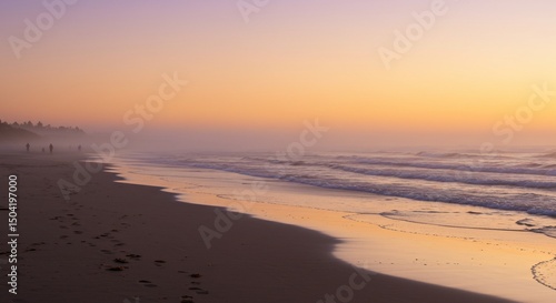 People stroll on beach during a hazy orange sunrise, waves breaking behind them