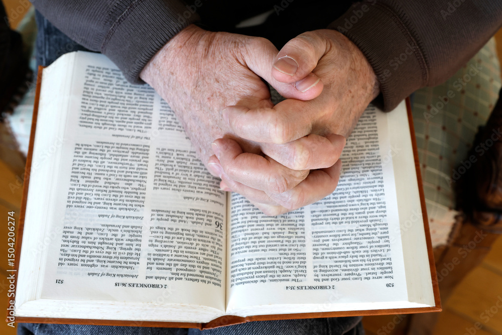 Naklejka premium Man praying to the Bible at home.