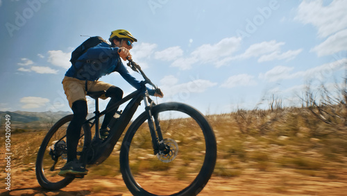 A thrilling close-up shot of a helmeted biker riding an e-bike on a dirt trail, showcasing the freedom and exhilaration of off-road cycling.