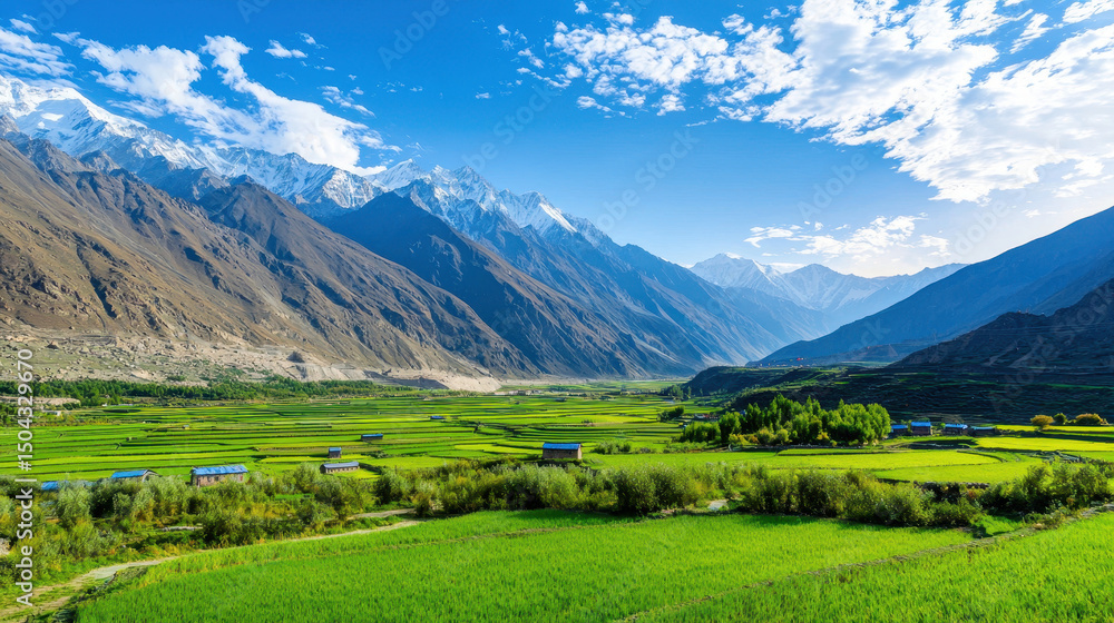 Naklejka premium Breathtaking landscape featuring lush green fields, majestic mountains, and clear blue sky, evoking sense of tranquility and natural beauty