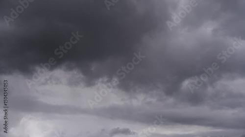 Timelapse of a dramatic sky with dark clouds. Thick dark cloud cover dominates the sky. The scene looks dramatic and foreshadows a storm or rain.