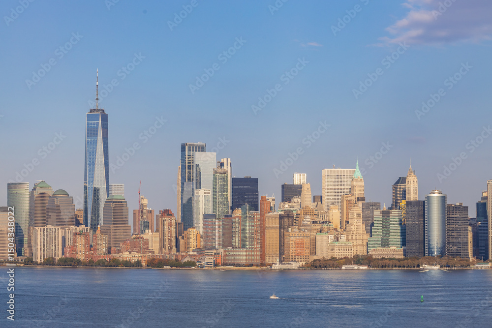 Obraz premium Panoramic view of Lower Manhattan skyline featuring One World Trade Center, seen from across the Hudson River on a clear day in New York City.