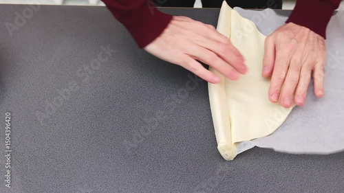 Hands rolling out fresh pizza dough on kitchen table - Food preparation process