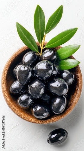 Fresh Black Olives in a Wooden Bowl With Green Leaves Placed on a White Backg...