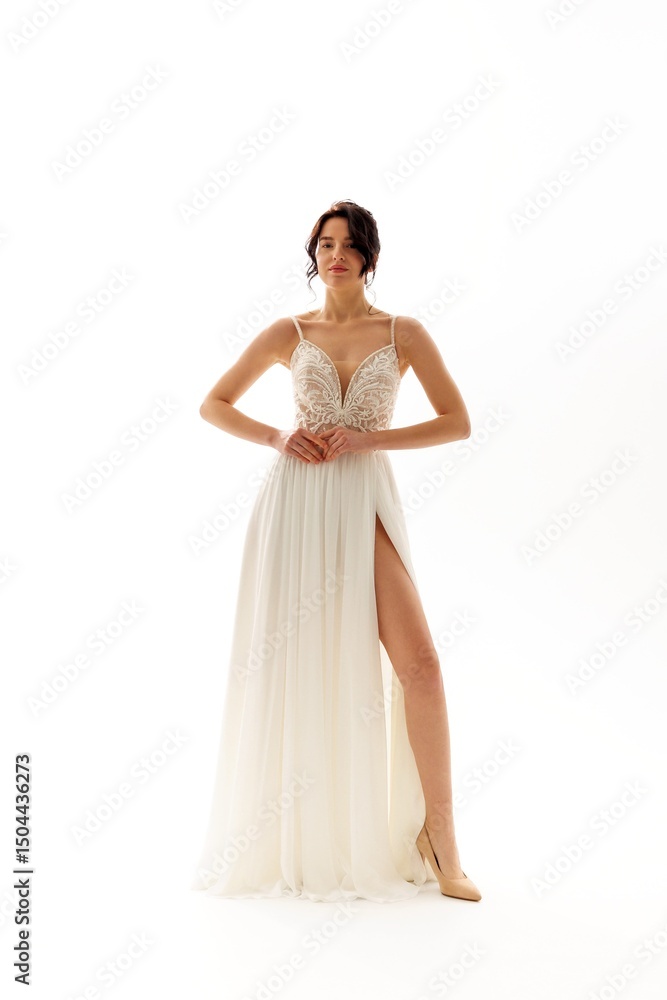 Fototapeta premium Elegant bride showcasing a stunning white gown with intricate detailing in a bright studio setting