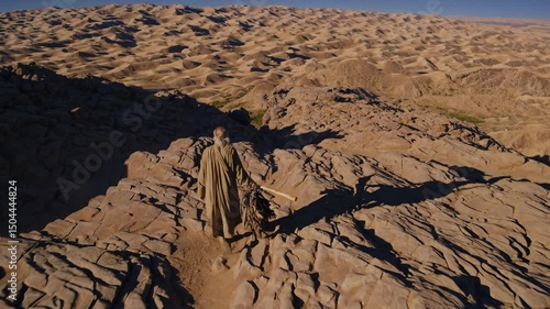 Desert landscape with a lone figure exploring rocky terrain near sunset in an arid region