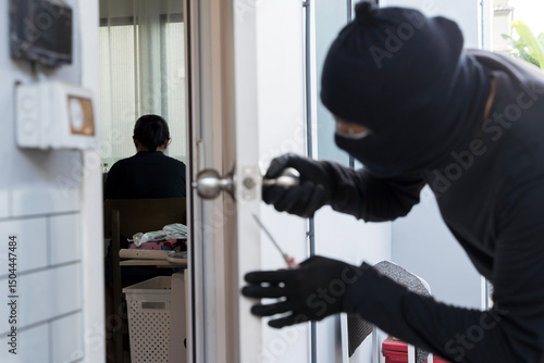 Wallpaper Mural Masked thief breaking into house while resident unaware, concept of burglary, home invasion, and security risk Torontodigital.ca