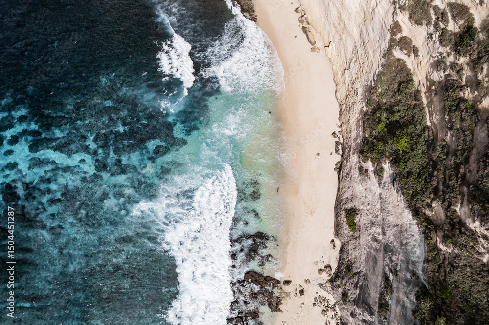 Obraz premium Turquoise water crashing on secluded sandy beach with cliff, aerial view