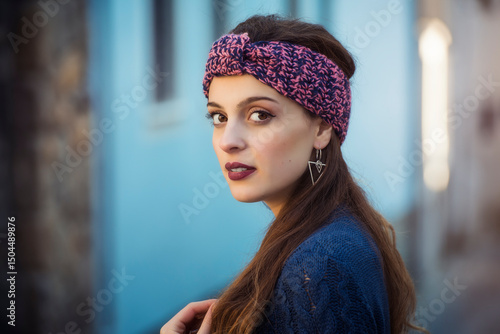 woman in town – stylish winter headband and blue knitwear in stone alley