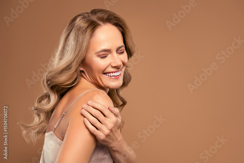 Beautiful mature woman smiling confidently in a stylish pose on a beige background