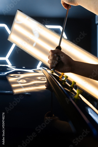 Quadro su tela Paintless car dent repair technician uses a slide hammer on glue tabs to restore car body panels