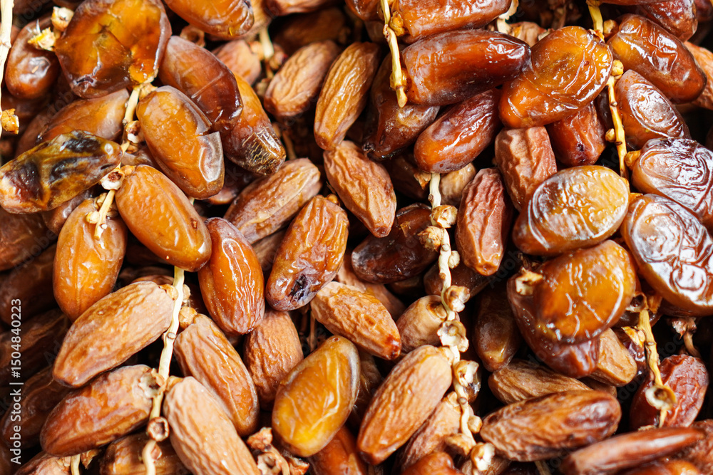 Obraz premium A close-up showcases the rich, glossy texture of dried dates, arranged in a dense pile. The natural light enhances their intricate details, highlighting the sweetness and depth.