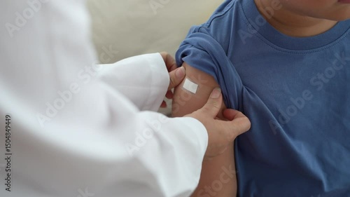 Asian boy got vaccinated and receiving wound patch from medical doctor, showing child health pediatric vaccine, influenza and covid prevention immunity support, hospital care, healthcare safety