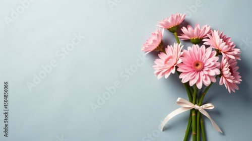 A delicate bouquet of pale pink blossoms tied with a silken ribbon rests on a soft blue background