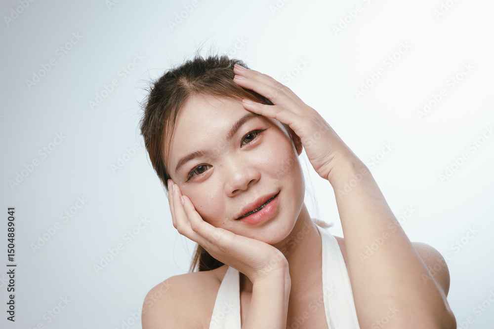 A young Asian woman with clear skin gently touches her face, showcasing natural beauty, skincare routine, and a healthy lifestyle. A young Asian woman with clear skin gently touches her face, showcasing natural beauty, skincare routine, and a healthy lifestyle.