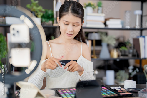 Asia woman beauty influencer makeup artist vlogger live streaming makeup tutorial on smartphone for social media photo