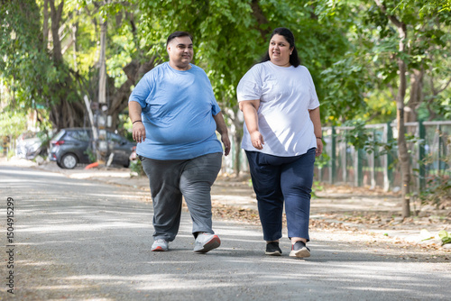 Obesity Concept- Indian couple walking together at summer park to loose weight. Plus size friends Fitness and healthy lifestyle. Fat man and woman outdoor.