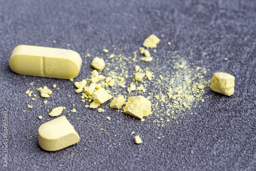 close up of broken medicine tablets on on a textured surface.