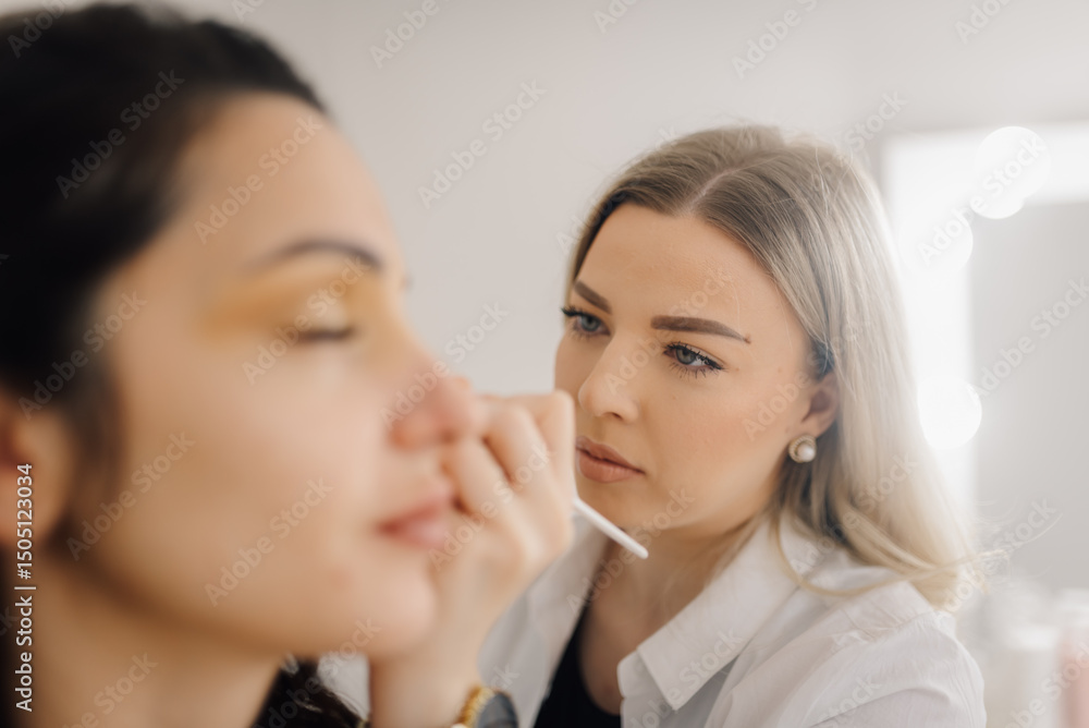 Makeup artist applying eyeshadow to model in beauty salon Makeup artist applying eyeshadow to model in beauty salon