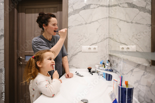 Mother and daughter brushing teeth together in the bathroom