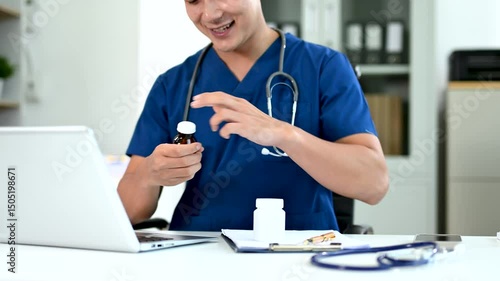 Asian male doctor in blue scrubs explaining medication during telehealth consultation. and modern medical services themes.