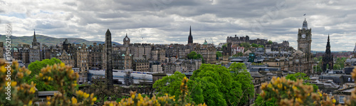 Edinburgh city skyline. Wide view of Edinburgh old town with historic buildings and monuments. Cloudy day in springtime. City panorama with clock tower, bell towers, a castle on the top of the hill.