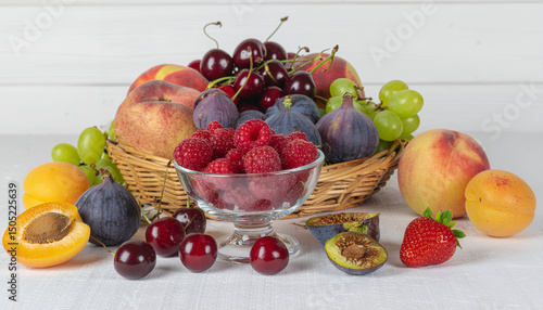 A vibrant still life featuring a variety of fresh fruits, including raspberries, cherries, and figs, set against a white background.