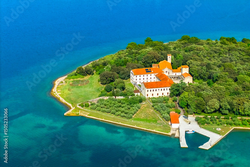 Krk, Croatia. Picturesque view from drone of the Franciscan monastery on Košljun Island, surrounded by dense forest and the turquoise Adriatic Sea. Hidden gem of Croatia