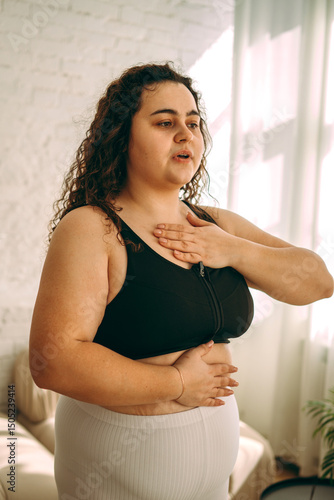 A young curly-haired plus-size woman doing breathing exercises.Healthy lifestyle.