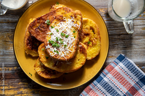 Fried bread with egg and milk cream or white cheese on top on a wooden table.