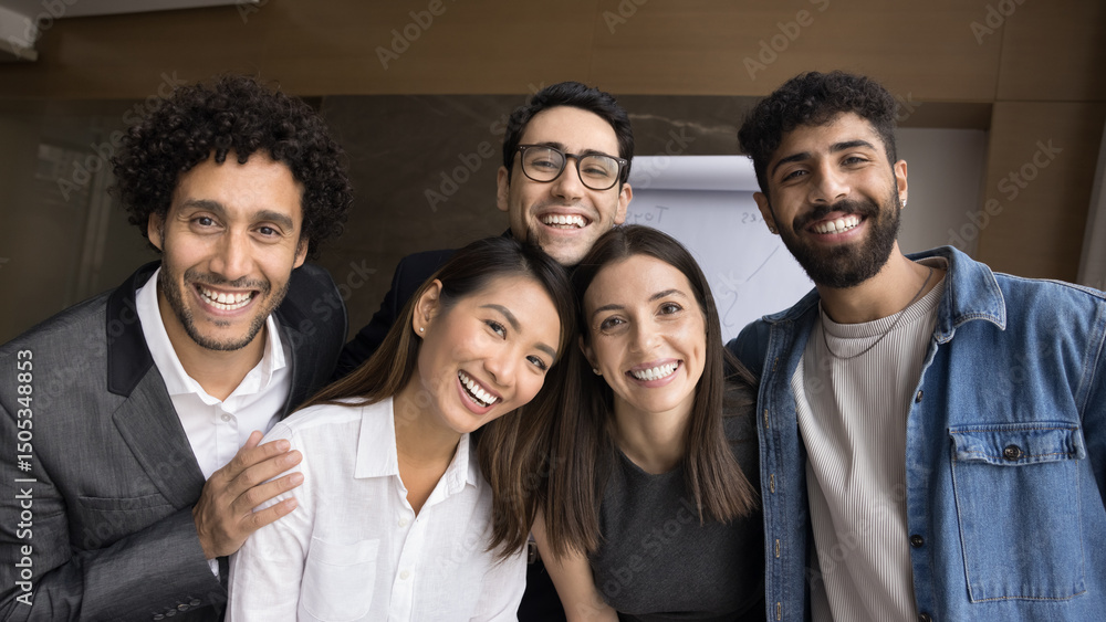 Informal setting. Group photo portrait diverse multiracial group five smiling friendly young people. Company of students office employees mates hugging looking at web camera making video call together Informal setting. Group photo portrait diverse multiracial group five smiling friendly young people. Company of students office employees mates hugging looking at web camera making video call together