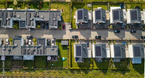 Rows of single-family houses on the city outskirts, featuring solar panels and green gardens, represent key elements of the real estate market, housing trends, mortgage loans.
