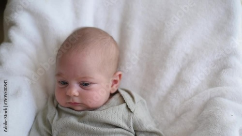 Smiling baby with blue eyes in olive overalls lies on back. Close-up.  First year of life and hygiene of child. Newborn - happiness for family. New worries and 