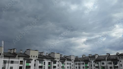 Movement of dark, white and gray clouds across the sky above the roofs of houses, background, time lapse