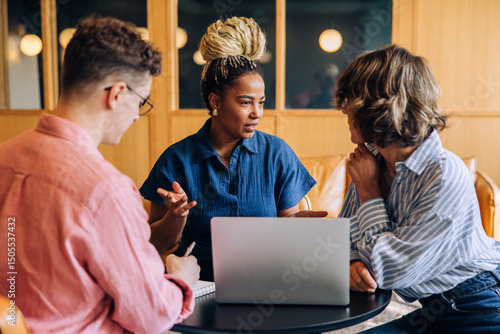 Fotografie Three young adults having a business discussion in a modern coworking office spa