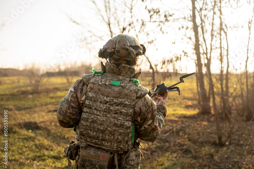 ukrainian soldier in camouflage is raising a small drone , preparing for takeoff in a forested landscape, with trees visible in the background. Soldier launches drone for reconnaissance 
