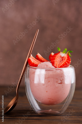 Whipped tofu and strawberry mousse dessert in a glass with pink spoon. Vegan food. Vertical orientation.