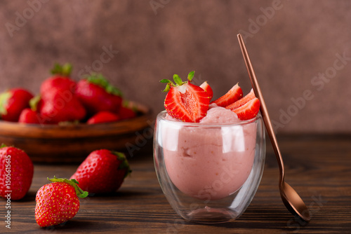 Whipped strawberry tofu and mousse dessert in a glass with pink spoon. Vegan food. Lactose and sugar free. Selective focus.