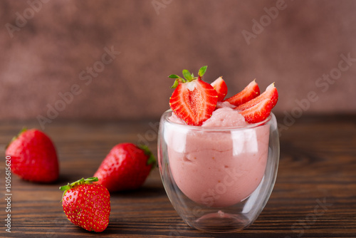 Vegan homemade strawberry tofu soy yogurt in a glass on a brown wooden table. Lactose and sugar free. Selective focus.