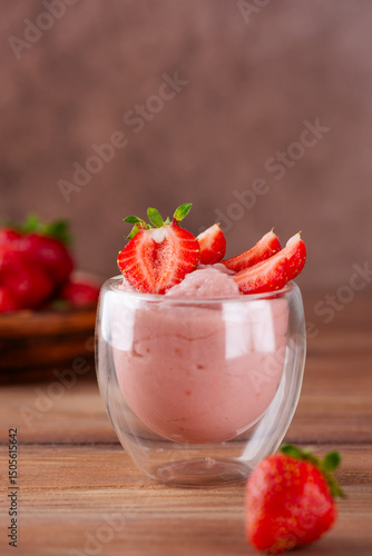 Strawberry tofu soy pink dessert in a glass on a wooden board. Lactose and sugar free. Selective focus. Vertical orientation.