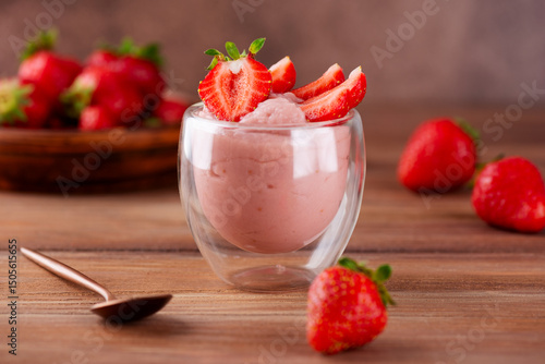 Whipped tofu and strawberry mousse dessert in a glass with spoon on a wooden table. Vegan food.