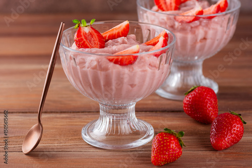 Tofu and strawberry mousse dessert in a glasses with spoon on a brown table. Vegan food. Lactose and sugar free.