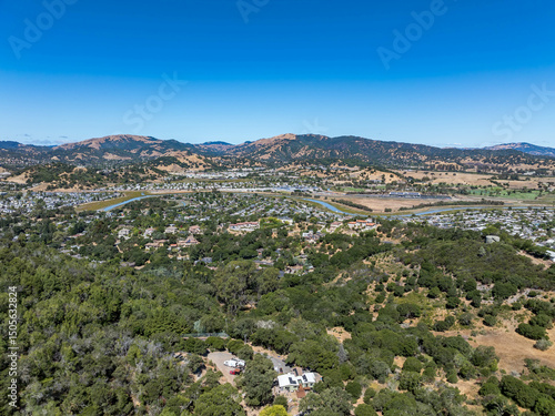 Aerial photos of a forested hillside in San Rafael, California, highlighting dense tree coverage, winding roads, and panoramic views of surrounding hills, residential properties, and the San Pablo Bay